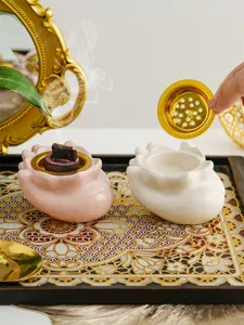 Vista dettagliata del bruciatore di incenso in ceramica a mano con vassoio dorato per aromaterapia.