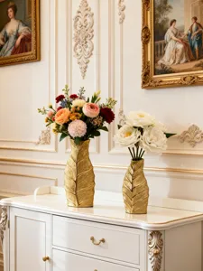 Vue rapprochée de vases en céramique dorée en forme de feuille avec des fleurs artificielles.