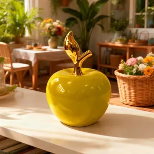 Primo piano di mela in ceramica gialla lucida con stelo dorato, decorazione d'interni.