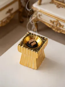 Primer plano detalle del quemador de incienso de cerámica dorada en mesa blanca con decoración.