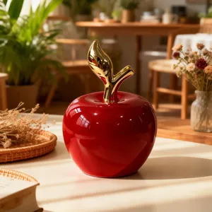 Primo piano della mela in ceramica rossa con stelo dorato, ideale per decorazioni.