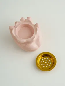 Vista dettagliata bruciatore di incenso in ceramica rosa con filtro dorato per decorazione.
