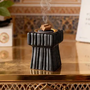 Primer plano del quemador de incienso de cerámica negra de lujo con rayas verticales y humo.