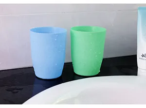 Primo piano dettagliato di tazze per collutorio in plastica smerigliata vicino al lavandino.