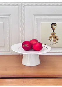 Detail view of modern minimalist white ceramic cake stand with ray texture for desserts.