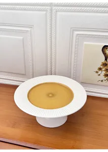 Ceramic cake stand detail view, white fluted rim with yellow center dessert plate display.