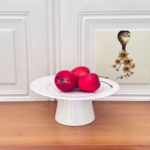 Modern minimalist white ceramic cake stand with rayed texture, dessert fruit display.