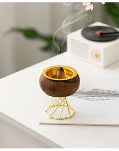 Close-up shot of the wooden incense burner with gold metal stand and burning cone.