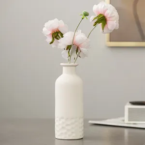 Gros plan d'un vase en céramique blanche minimaliste nordique avec de belles fleurs roses.