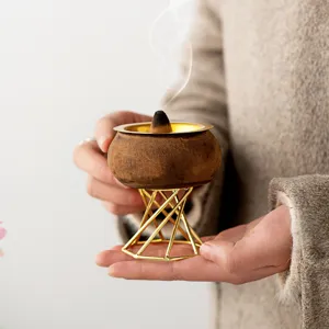 Handmade wooden cone incense burner with stylish gold metal geometric stand for home decor.