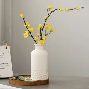 Vue détaillée du vase en céramique blanche minimaliste nordique avec des fleurs jaunes.