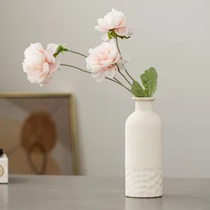 Vue détaillée d'un vase en céramique blanche minimaliste nordique avec des fleurs roses.