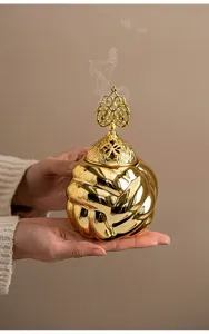 Detailed close-up view of the modern golden ceramic incense burner with its hollow carved lid.