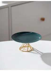 Modern minimalist ceramic cake plate detail, dark green dish with gold metal geometric stand.