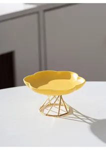 Modern minimalist ceramic cake plate with gold metal stand, stylish fruit dessert dish.