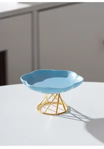Ceramic fruit dessert plate detail showing blue cloud-shaped dish on gold geometric metal stand.