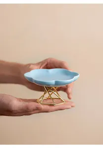 Close-up detail of the ceramic dessert plate with a geometric gold metal stand, elegant decor.