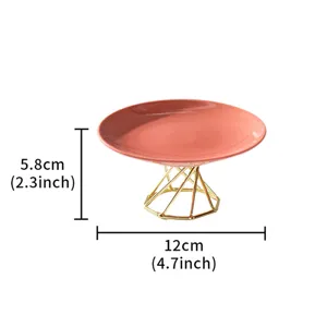 Ceramic cake stand detail view, pink plate with gold geometric metal base design for dessert display.
