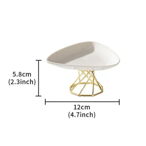 Detail view of modern minimalist ceramic triangle tray with gold geometric metal stand.