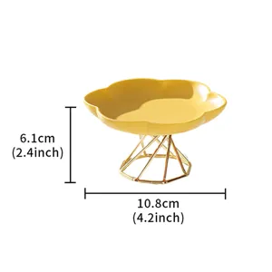 Modern minimalist yellow ceramic fruit plate with gold metal geometric stand detail view.