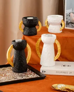 Dettaglio portacandele in resina nero e bianco con manici dorati per decorazione tavola.