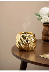 Nahaufnahme eines luxuriösen goldenen geknoteten Keramik-Räucherfasses auf einem Holztisch.