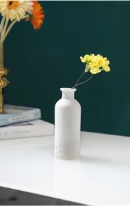 Gros plan détaillé sur le vase en céramique blanche minimaliste moderne avec des fleurs.