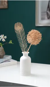 Vase en céramique blanche minimaliste nordique avec arrangement floral artificiel doré.