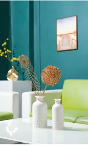 Vue détaillée d'un vase en céramique blanche minimaliste avec composition florale dorée dans le salon.