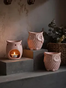 Close up of pink ceramic owl candle holder and aroma diffuser in cozy rustic home setting style.