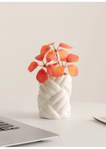 Minimalist white ceramic vase with braided texture and artificial autumn leaves detail display