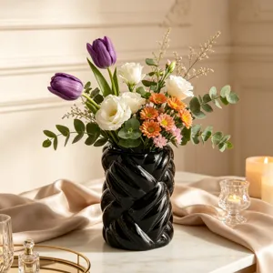 Modern minimalist black ceramic yarn ball vase cylindrical floral arrangement home decor piece.