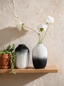 Detail view of minimalist wabi-sabi black and white gradient resin vases on a wooden shelf.