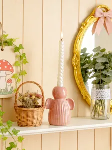 Detail du bougeoir ange en ceramique rose place sur etagere pour decoration de table chic.