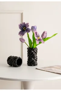 Modern minimalist black ceramic twisted vase with elegant purple artificial tulips for home decor.