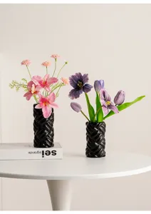 Detailed view of modern minimalist black ceramic cylindrical vases arranged with floral decor.