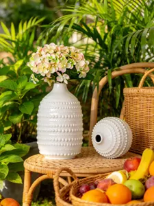 Gros plan détaillé d'un vase en céramique blanche texturé, présenté dans un décor verdoyant.