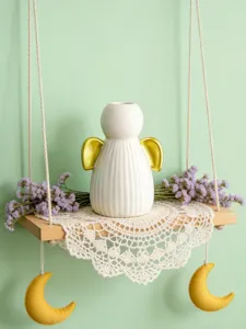 Vue détaillée du bougeoir ange en céramique blanche sur étagère suspendue avec fleurs.