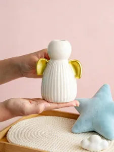 Vue détaillée d'un bougeoir ange en céramique moderne, design blanc et or, idéal pour déco d'intérieur.