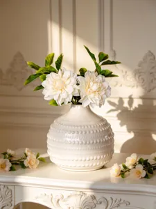 Vue détaillée d'un vase en céramique blanche nordique avec relief perlé texturé.