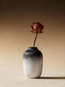 Close-up detail of a minimalist black and white gradient resin vase with dry flower.