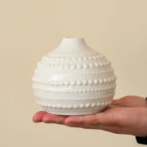 Gros plan d'un vase en céramique blanche avec texture à pois pour décoration de table.