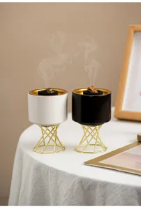 Modern Nordic ceramic incense burner detail showcasing black and white vessels on gold stands.