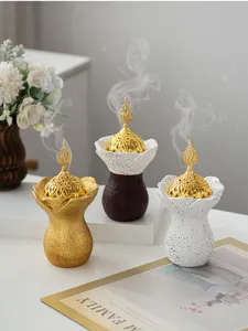 Vue détaillée de brûleurs d'encens en résine avec couvercles dorés et socles texturés élégants.