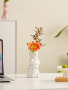 Detail shot of the white ceramic rabbit vase with artificial flower on a clean wooden table.