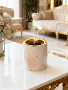 Nahaufnahme des luxuriösen rosa Marmor Keramik Weihrauchbrenners mit Goldrand und Rauch.