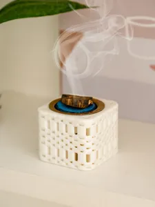 Detail view of a creative square incense burner with burning wood and delicate smoke.