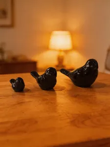 Close-up shot of cute ceramic bird figurines on a wooden table, perfect for cozy room decor.