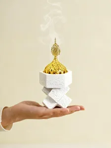 Close-up detail of Middle Eastern resin incense burner with gold dome and cross base.
