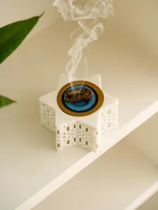Close-up of white star incense burner with smoking incense, minimal modern home decor detail shot.